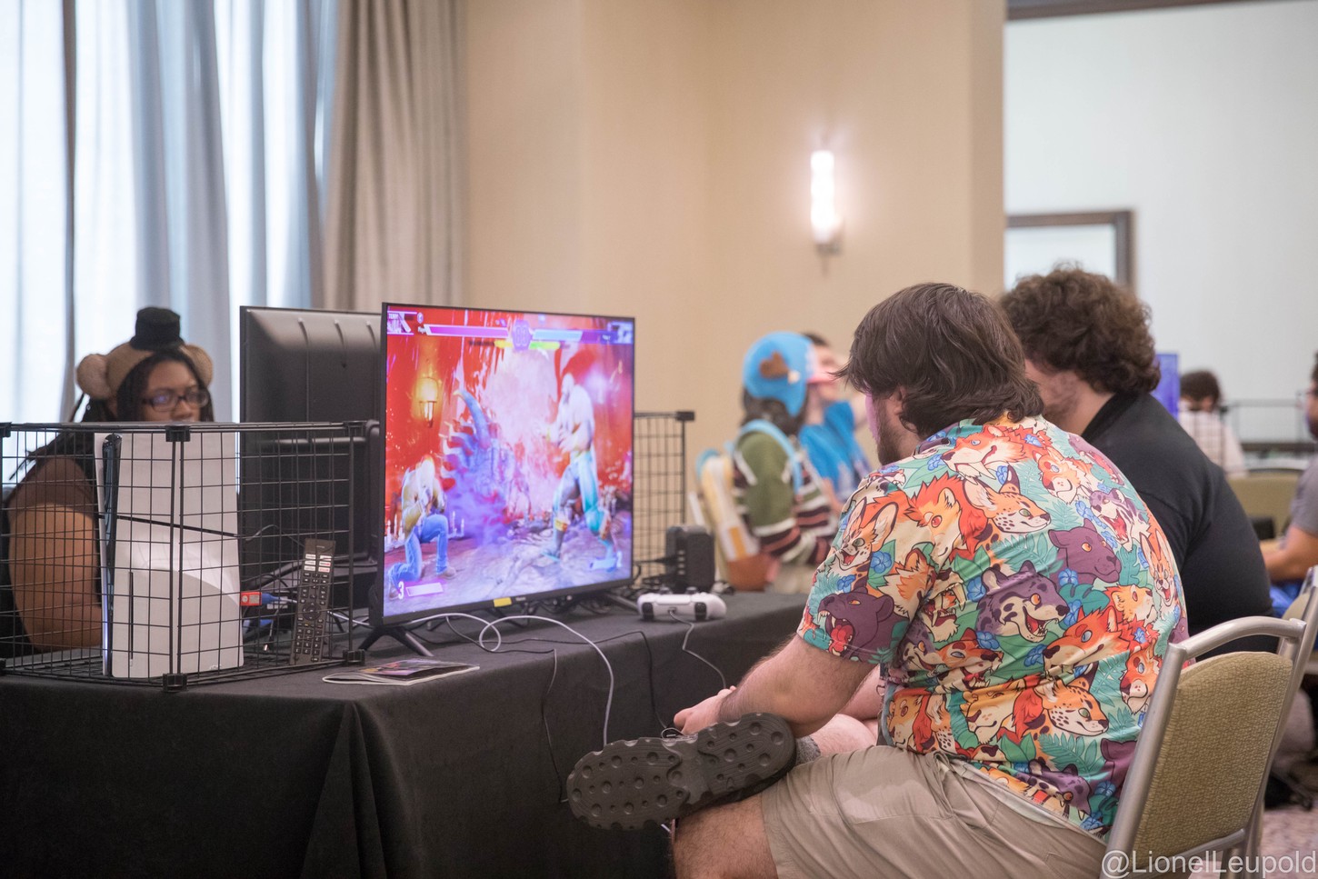 A photograph of two people sitting in front of a television playing a fighting game.